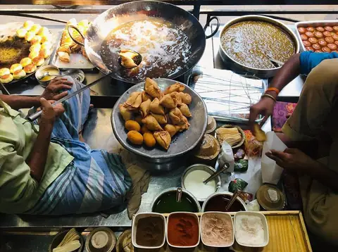 The Ram Bhandar counter from above: samosas frying in the kadhai, aloo tikki, gulab jamun, chutneys and spices